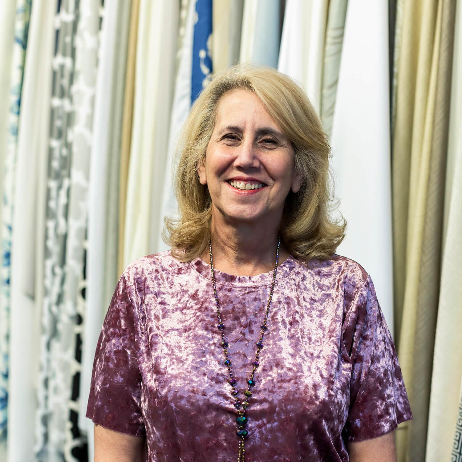 A woman smiles in front of a wall of drapery fabric samples
