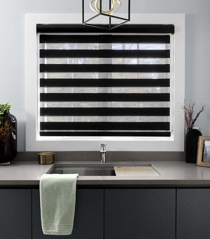 A black roller shade covers a large window in a modern home.
