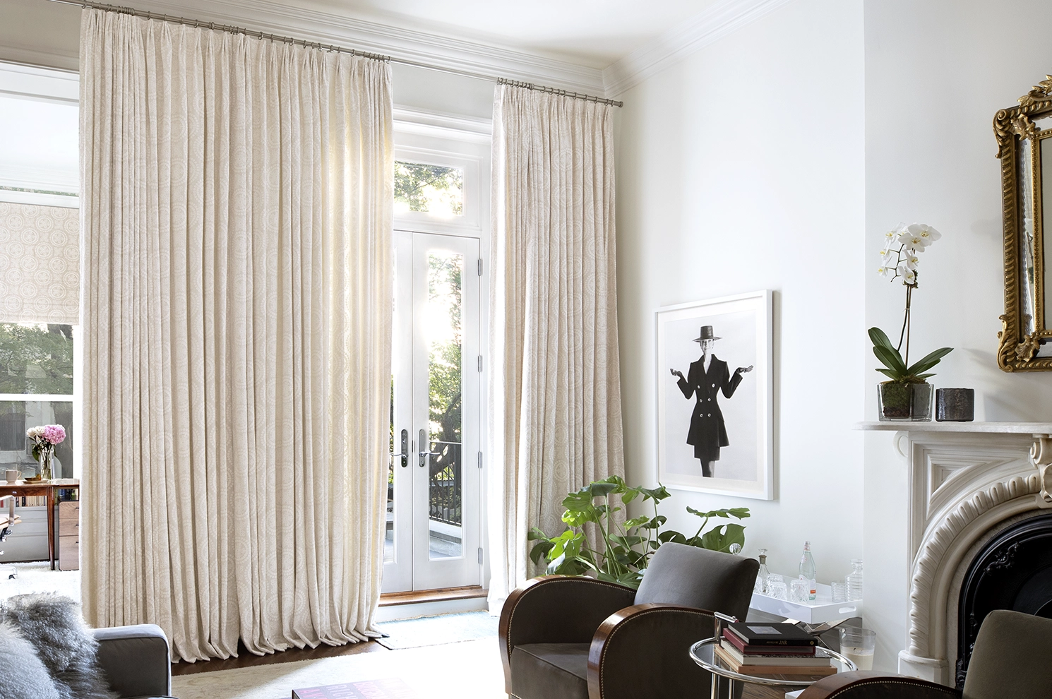 Cream curtains cover a wall of French doors in a chic and modern living room.