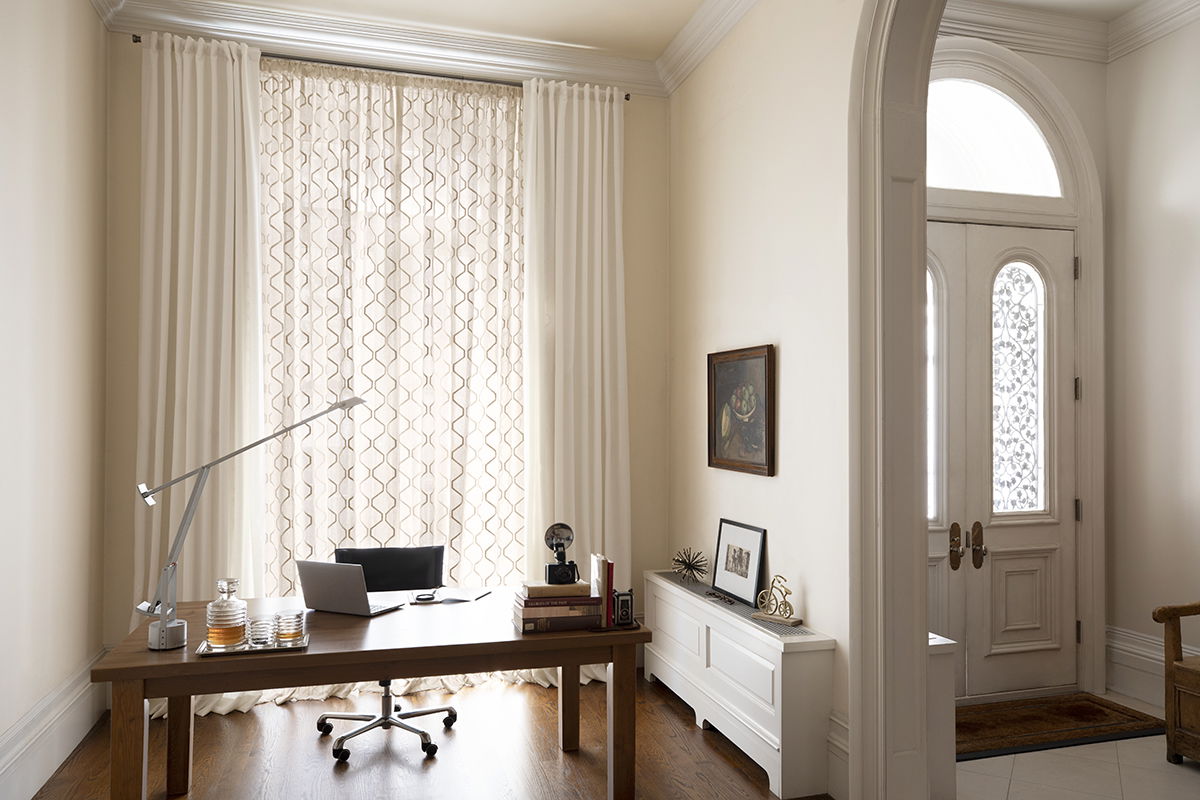 A cozy neutral home office with floor-to-ceiling drapery.