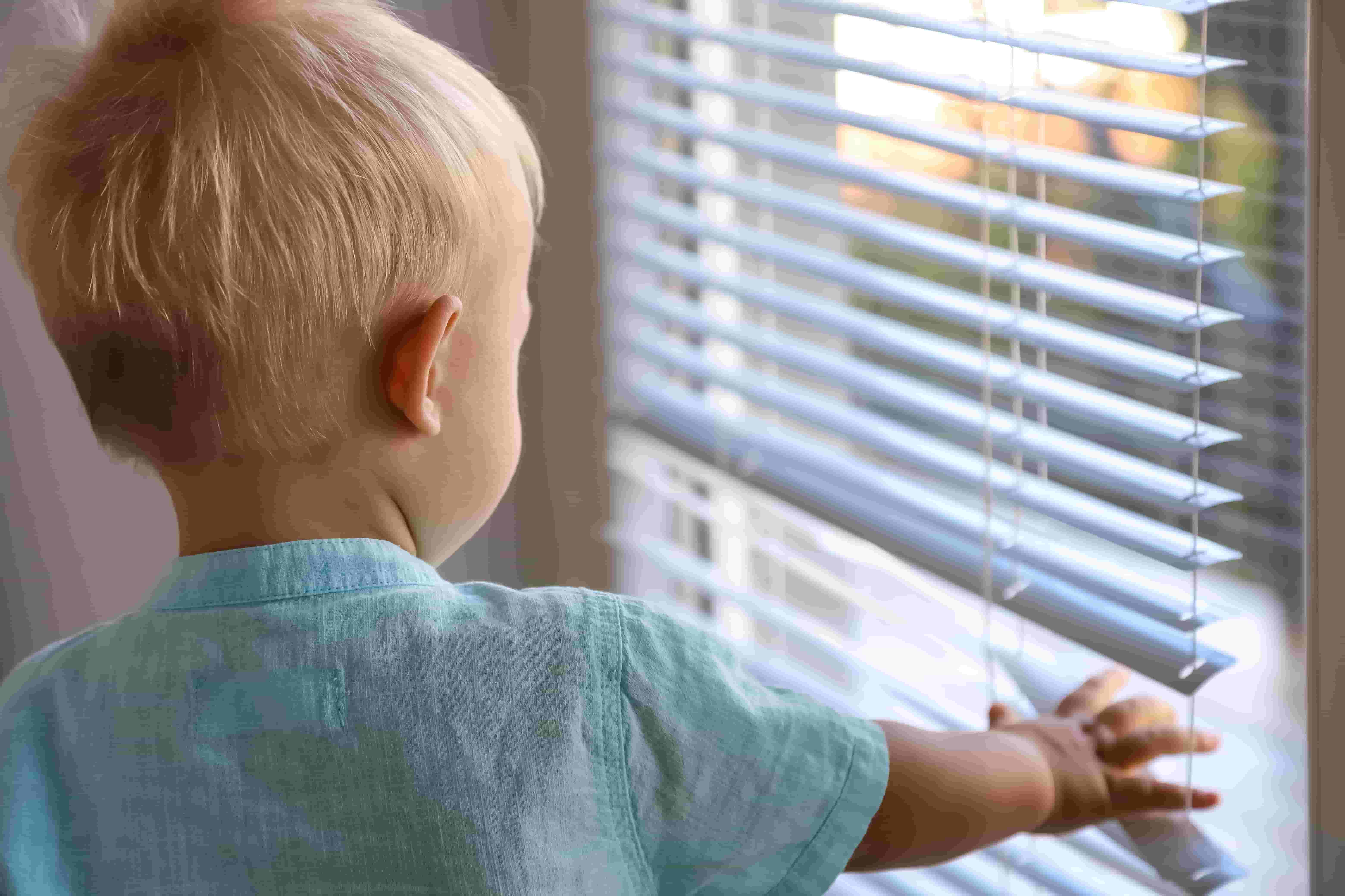 A toddler reaches for aluminum mini blinds