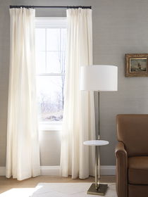 White drapery in a living room with a nearby lamp, creating a cozy and elegant ambiance.