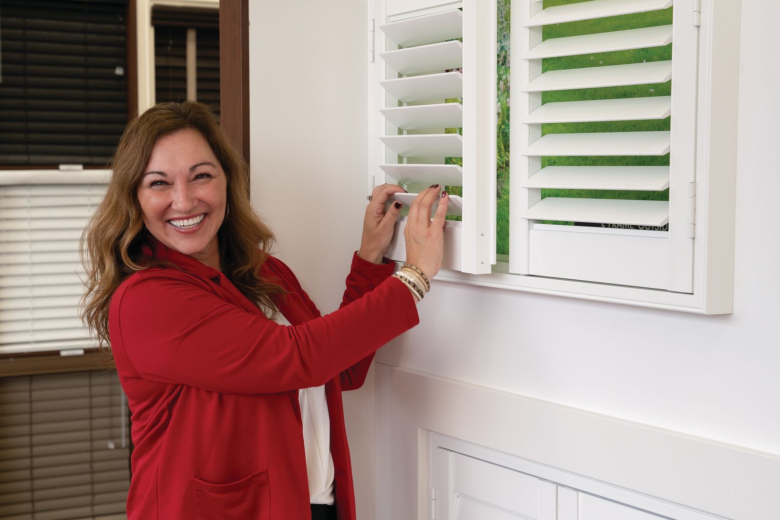 Smiling lady opening window blinds