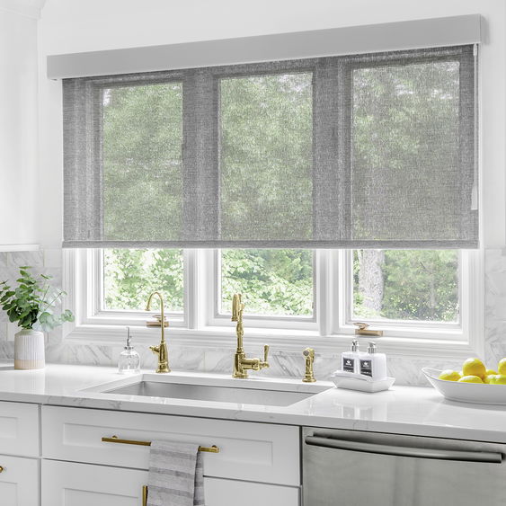 Outside mount solar roller shades cover a large window in a modern kitchen.