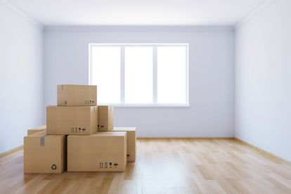 An empty room with moving boxes features a window with no window covering